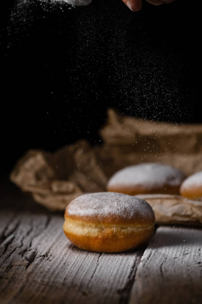 istock Donut filled with jam on black background, sprinkled with sugar. 1368916257