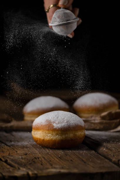 istock Donut filled with jam on black background, sprinkled with sugar. 1368916272