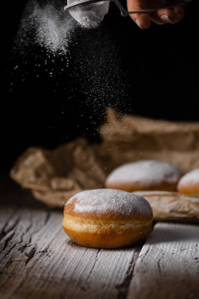 istock Donut filled with jam on black background, sprinkled with sugar. 1368916273