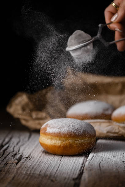 istock Donut filled with jam on black background, sprinkled with sugar. 1368916274