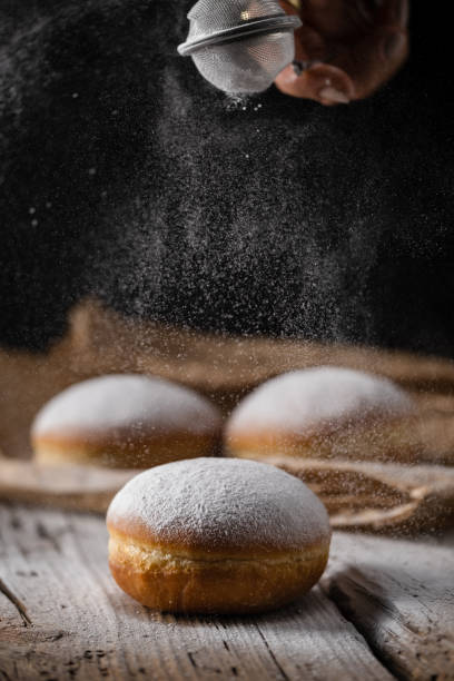 istock Donut filled with jam on black background, sprinkled with sugar. 1368916304