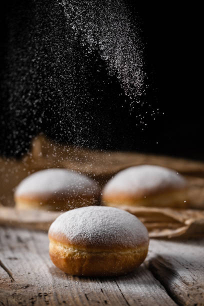 istock Donut filled with jam on black background, sprinkled with sugar. 1368916308