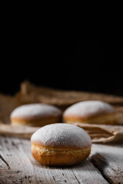 istock Donut filled with jam on black background, sprinkled with sugar. 1368916329