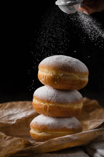 istock Donut filled with jam on black background, sprinkled with sugar. 1368916337