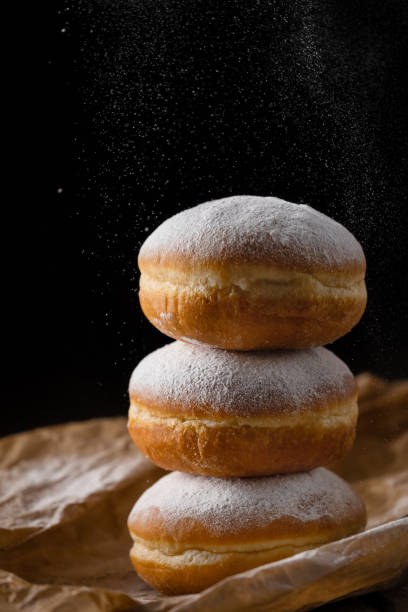 istock Donut filled with jam on black background, sprinkled with sugar. 1368916341