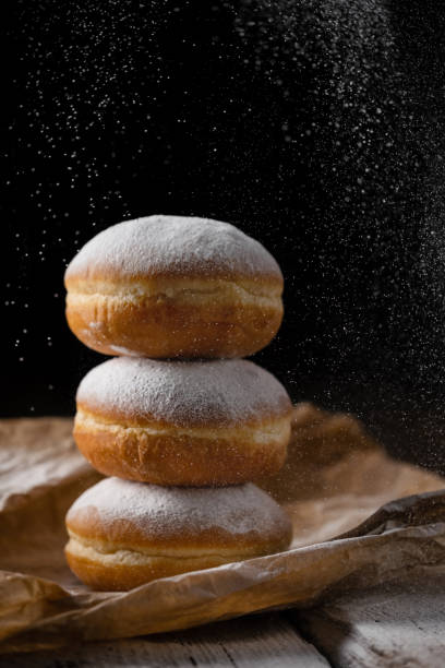 istock Donut filled with jam on black background, sprinkled with sugar. 1368916356