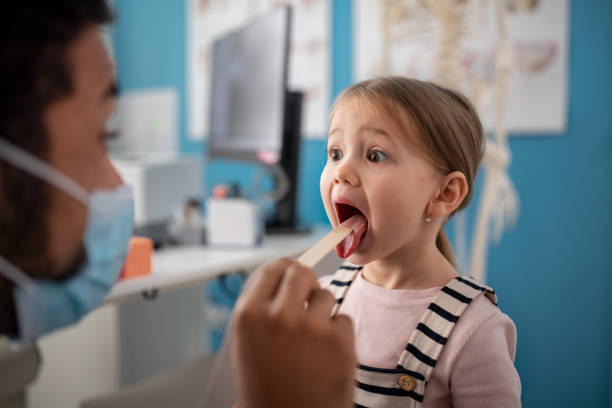 young male doctor checking little girl's throat in his office. - 喉嚨 個照片及圖片檔