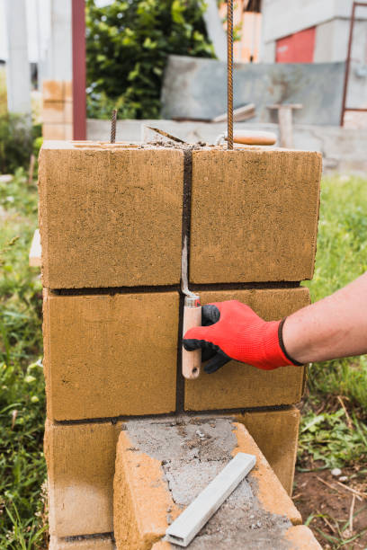 istock A professional bricklayer builds pillars for a stone fence from cement blocks 1368917028
