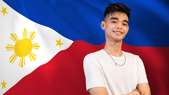 A proud and patriotic young Filipino male, in front of a waving Philippine flag.
