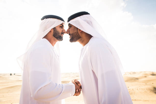 Arabian men with kandora walking in the desert - Portrait of two middle eastern adults with traditional arabian dish dasha dress