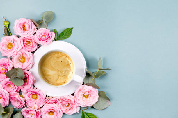 istock A cup of coffee, pink roses and eucalyptus branches on a light blue background. Beautiful spring card with free space for text 1368918770