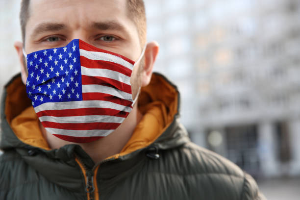 istock Man wearing mask with USA flag pattern outdoors, closeup. Dangerous virus 1368919253