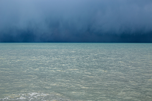 An atmospheric stormy sea with a rich blue color of water and clouds. Minimalistic storm landscape.