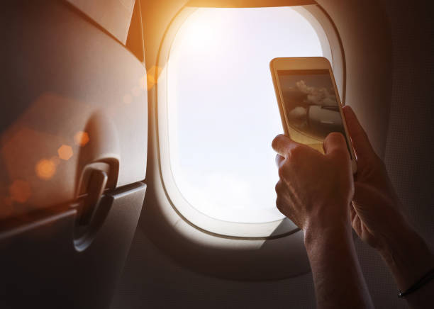 istock Female using her smartphone for photographing clouds and aircraft engine through the porthole. Active traveling and flying by planes aviation transport concept image. 1368922132