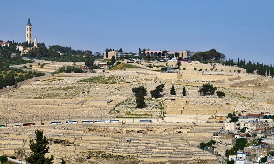 East Jerusalem, Palestine, May 1, 2019: Mount of Olives with the Seven Arches Hotel and the The Russian Church (left) on a sunny spring day. In the foreground is the old Jewish cemetery.