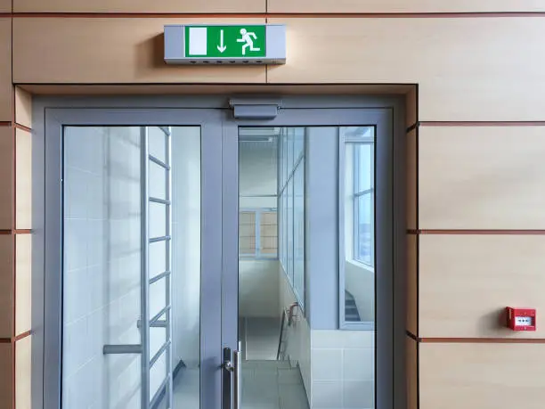 Photo of Emergency exit with glass door in airport office building. Emergency fire doors.