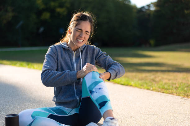 Young sporty woman has pain in left knee stock photo