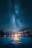istock Beautiful sunrise over snowy forest with an epic milky way on the sky 1368928069