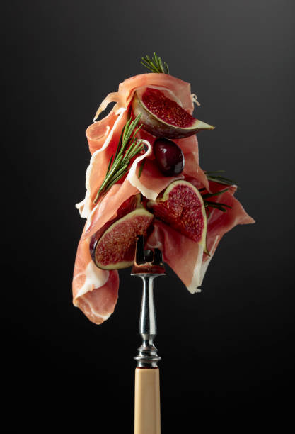 istock Prosciutto with figs, rosemary, and red olives on a fork. 1368930044