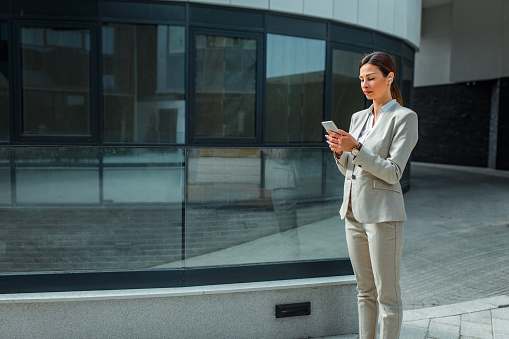 Young businesswoman with earphones, in front of her workspace using cellphone