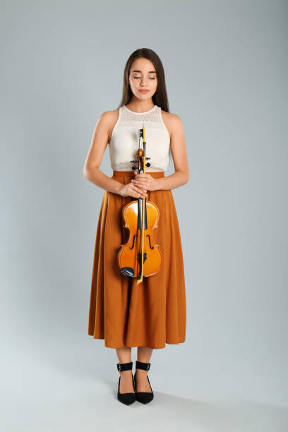 istock Beautiful woman with violin on grey background 1368933861