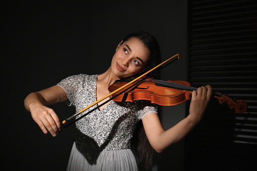 Young woman in turquoise blue dress playing violin