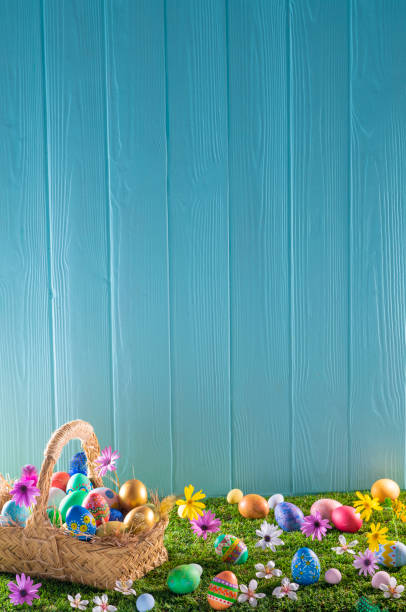 istock Easter eggs basket on turf grass and blue wooden wall with spring flowers 1368936026
