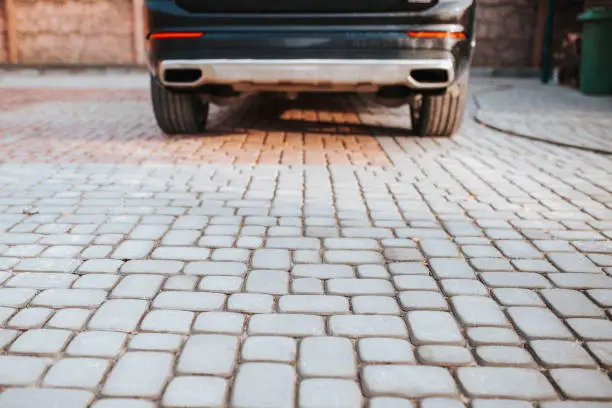 Car in the courtyard on stone cobblestones - a durable, stable all-weather parking cover near the garage