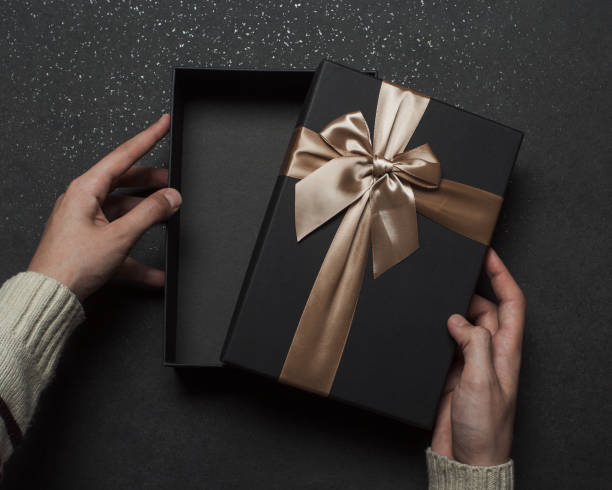 istock A guy in a sweater opens a gift with a red ribbon 1368937480