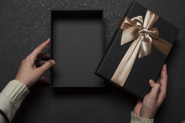 istock A guy in a sweater opens a gift with a red ribbon 1368937500