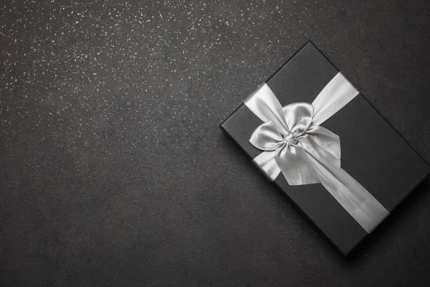 istock Black gift box with a silver ribbon and a large bow on a granite dark background. Place for the inscription 1368937737