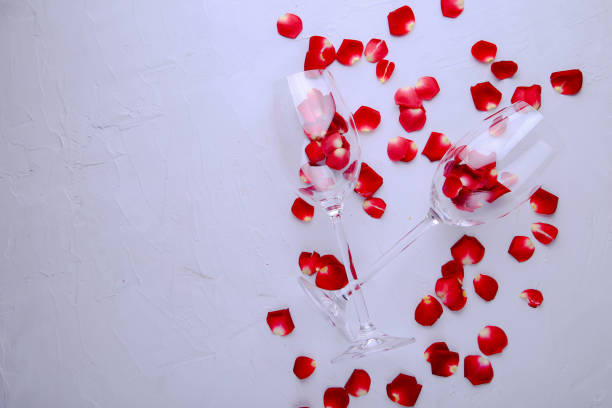 Glasses with rose petals on a gray background with space for text.