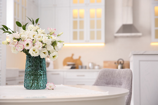 Bouquet of beautiful flowers on table in kitchen, space for text. Interior design