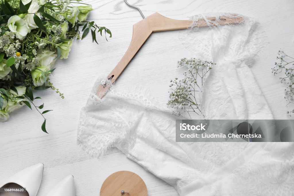 Beautiful wedding dress, engagement ring and flowers on white wooden background, flat lay Wedding Dress Stock Photo