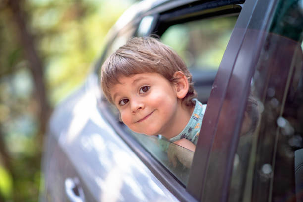 istock little boy with head leaned through the open window of a car 1368949045