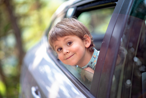 little boy with head leaned through the open window of a car