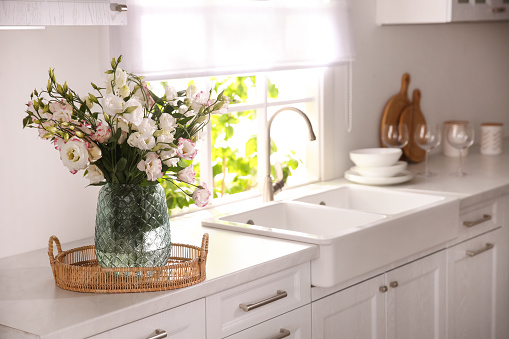 Bouquet of beautiful flowers on countertop in kitchen, space for text. Interior design