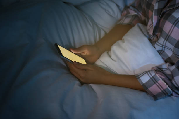 istock Woman using smartphone in bed at night, closeup. Nomophobia and sleeping disorder problem 1368951127