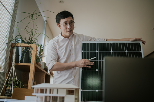 Asian salesman explaining about solar panel system by video conference with his important costumer at home.