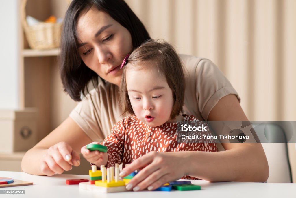 Social emotional development of children with down syndrome, the girl plays in the classroom with educational toys Disability Stock Photo