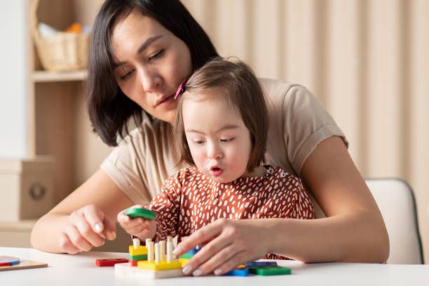 Social emotional development of children with down syndrome, the girl plays in the classroom with educational toys Social emotional development of children with down syndrome, the girl plays in the classroom with educational toys down syndrome stock pictures, royalty-free photos & images