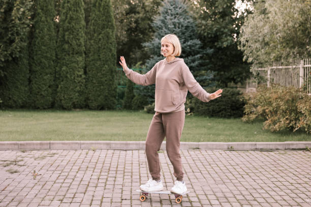 istock Pretty woman learns to skate to skateboard on a autumn day 1368953473
