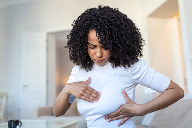 jovem afro-americana palpando seu peito sozinha que ela se preocupa com o câncer de mama. conceito de saúde e câncer de mama - breast sensuality women touching - fotografias e filmes do acervo