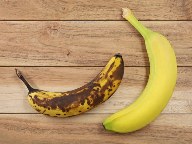 vista superior de banana madura marrom e madura amarela em fundo de madeira, comparação de bananas - banana bunch yellow healthy lifestyle - fotografias e filmes do acervo