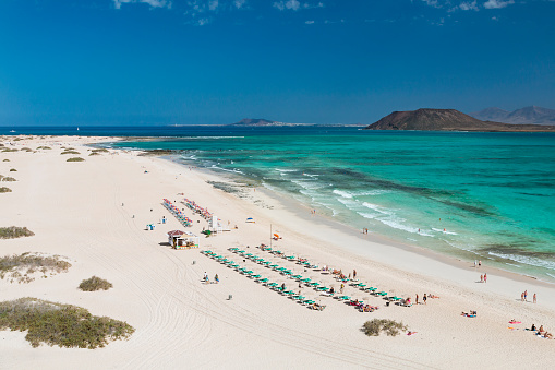 Aerial view of Corralejo Beach and turquoise water in Fuerteventura, Spain with Isla de Lobos and Lanzarote in the background.