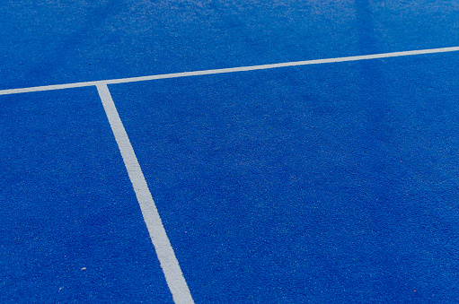 White lines of a blue paddle tennis court. Racket sports concept