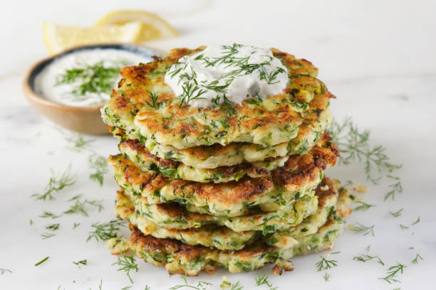 Greek Zucchini and Feta Fritters Greek Zucchini and Feta Fritters (Keftedes) with Green Onion, Dill and Tzatziki courgette stock pictures, royalty-free photos & images