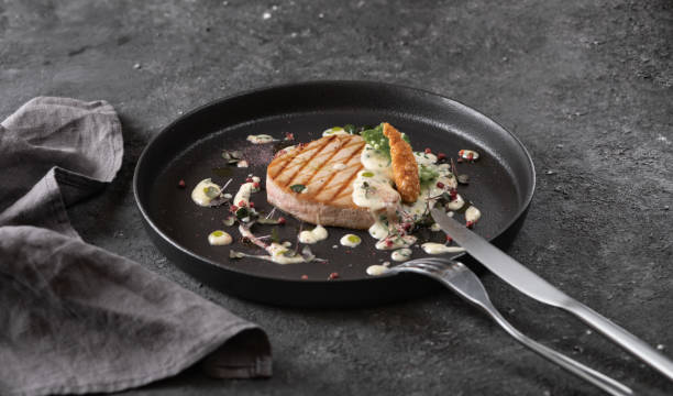 istock grilled tuna steak with sauce, black round plate on dark background 1368961472