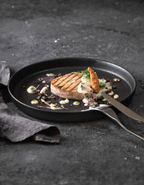 istock grilled tuna steak with sauce, black round plate on dark background 1368961491