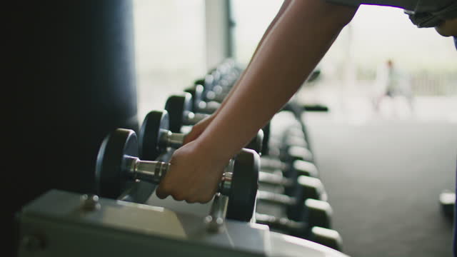 woman takes dumbbell in gym. Closeup of dumbbells row